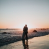 A silhouette of a couple standing together, with a beautiful sky in the background