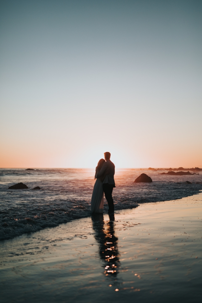 A silhouette of a couple standing together, with a beautiful sky in the background