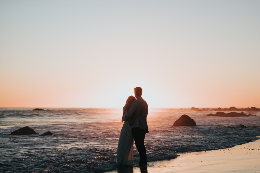 A silhouette of a couple standing together, with a beautiful sky in the background